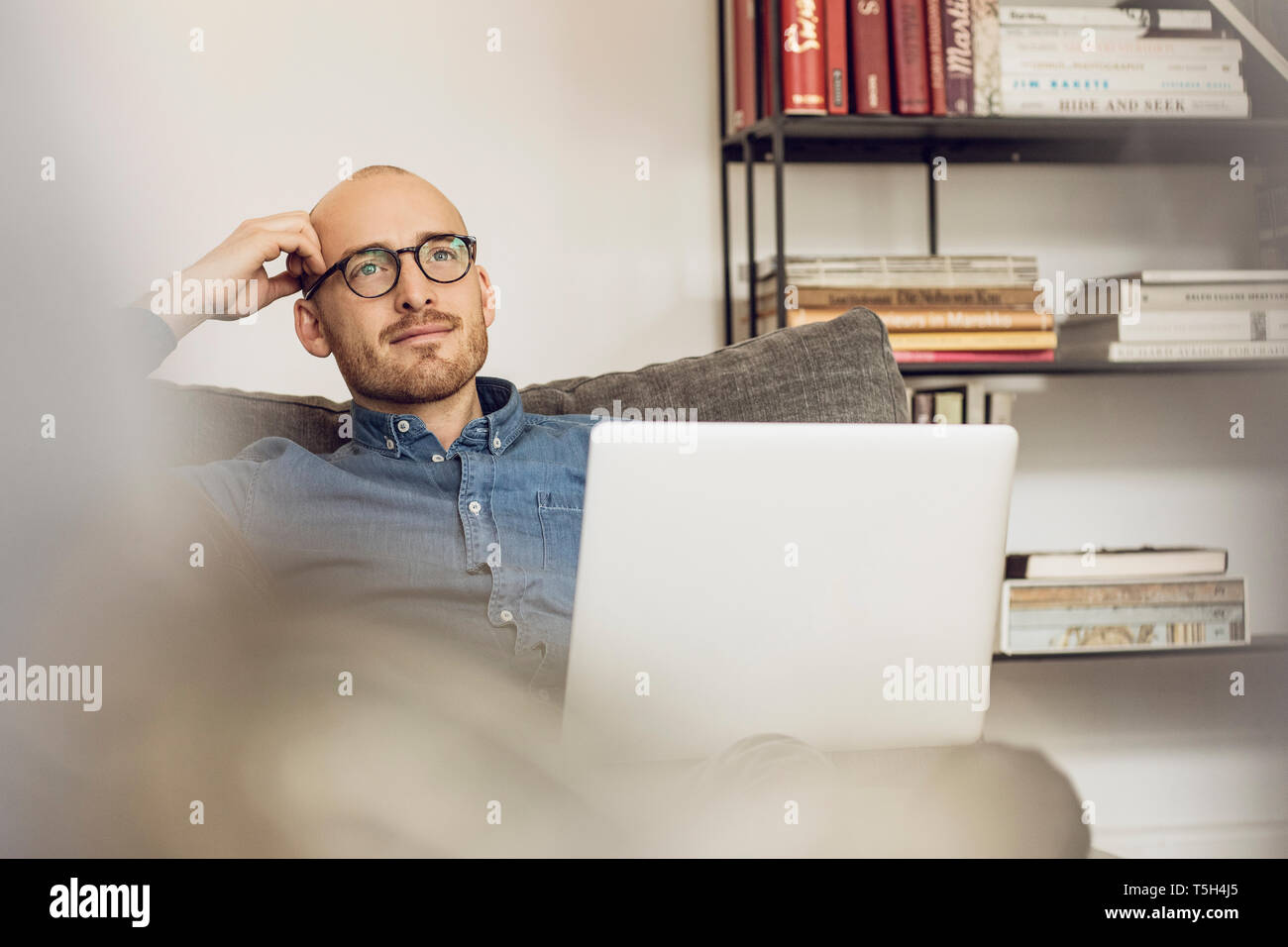 Man sitting on couch, usinag laptop Stock Photo