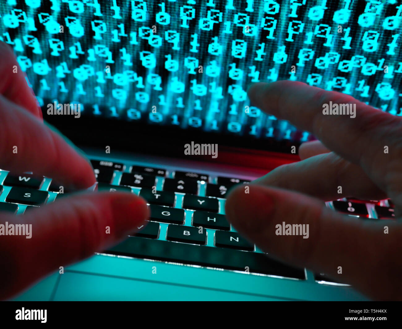 Hacker coding a computer virus infecting a laptop Stock Photo
