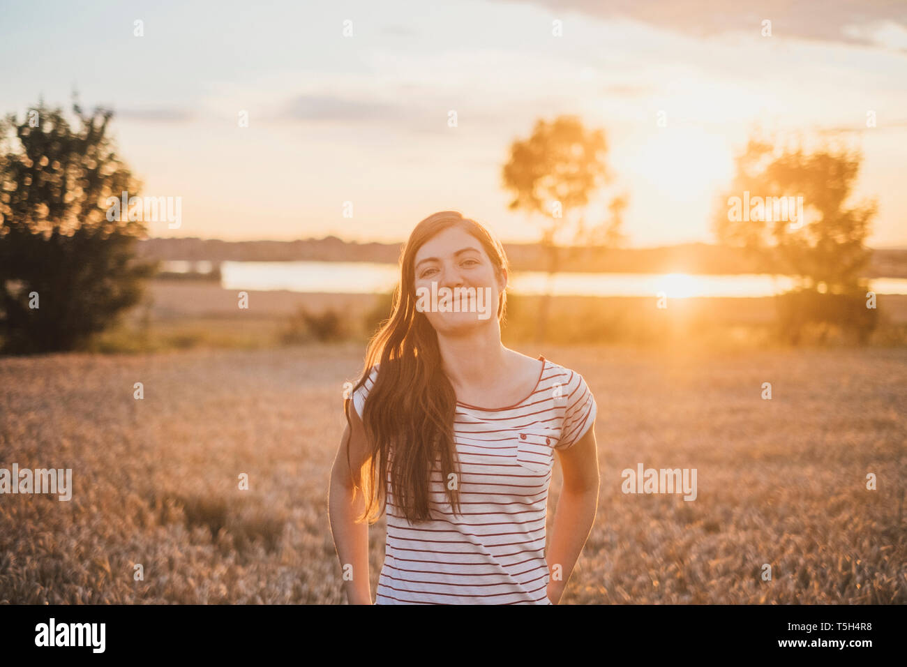 Portrait of smiling young woman in nature at sunset Stock Photo - Alamy