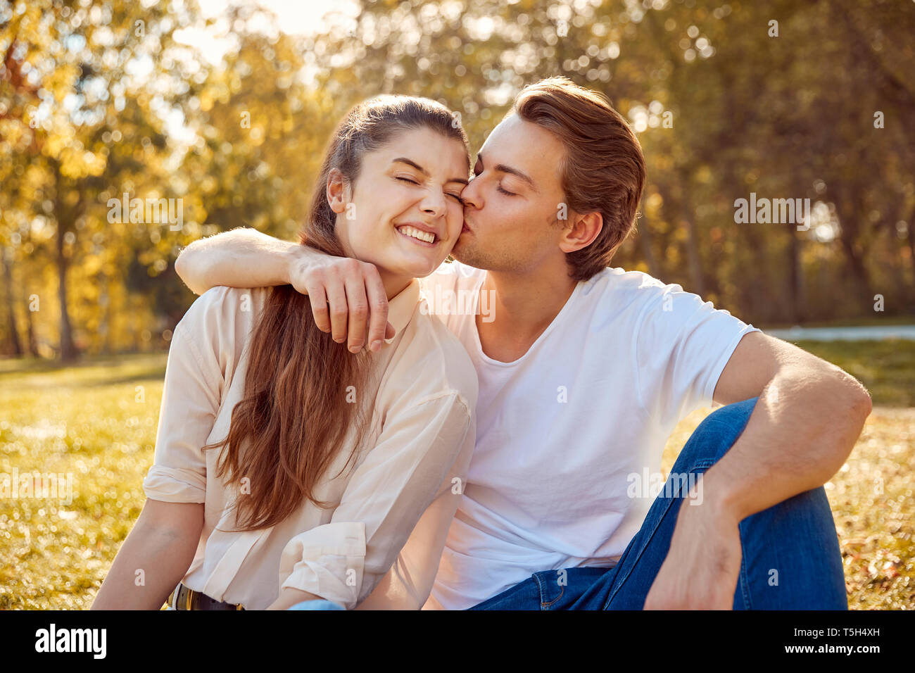 Happy young couple kissing at a park Stock Photo - Alamy