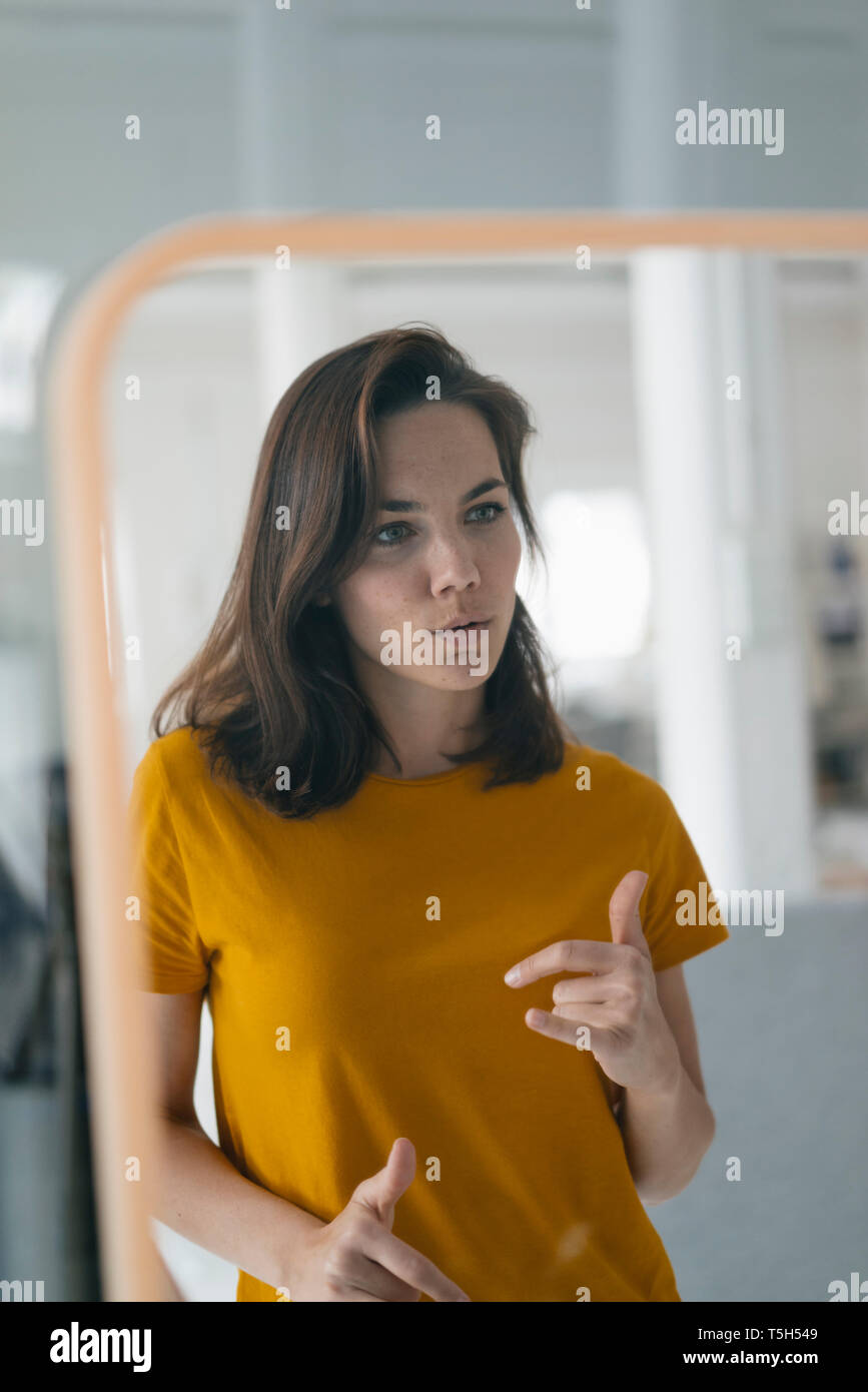 Pretty woman standing in front of mirror, talking Stock Photo