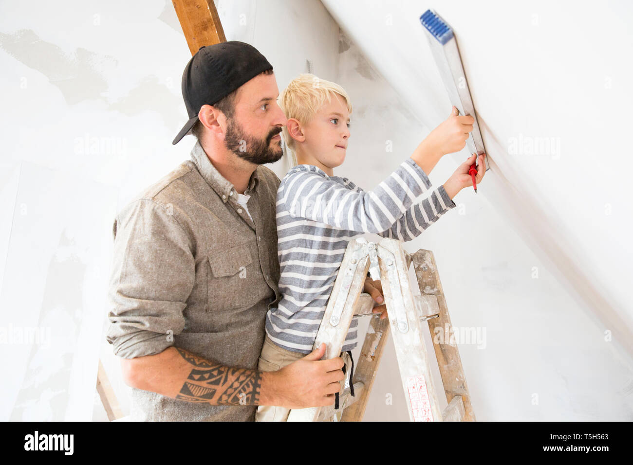 Father and son working on loft conversion using water level Stock Photo