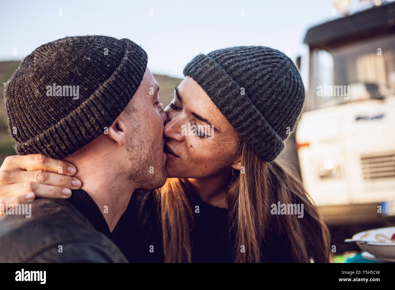 Kissing couple wearing wooly hats Stock Photo - Alamy