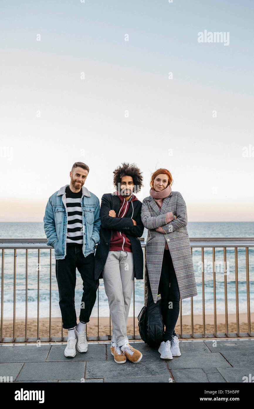 Portrait of three friends standing at the sea Stock Photo