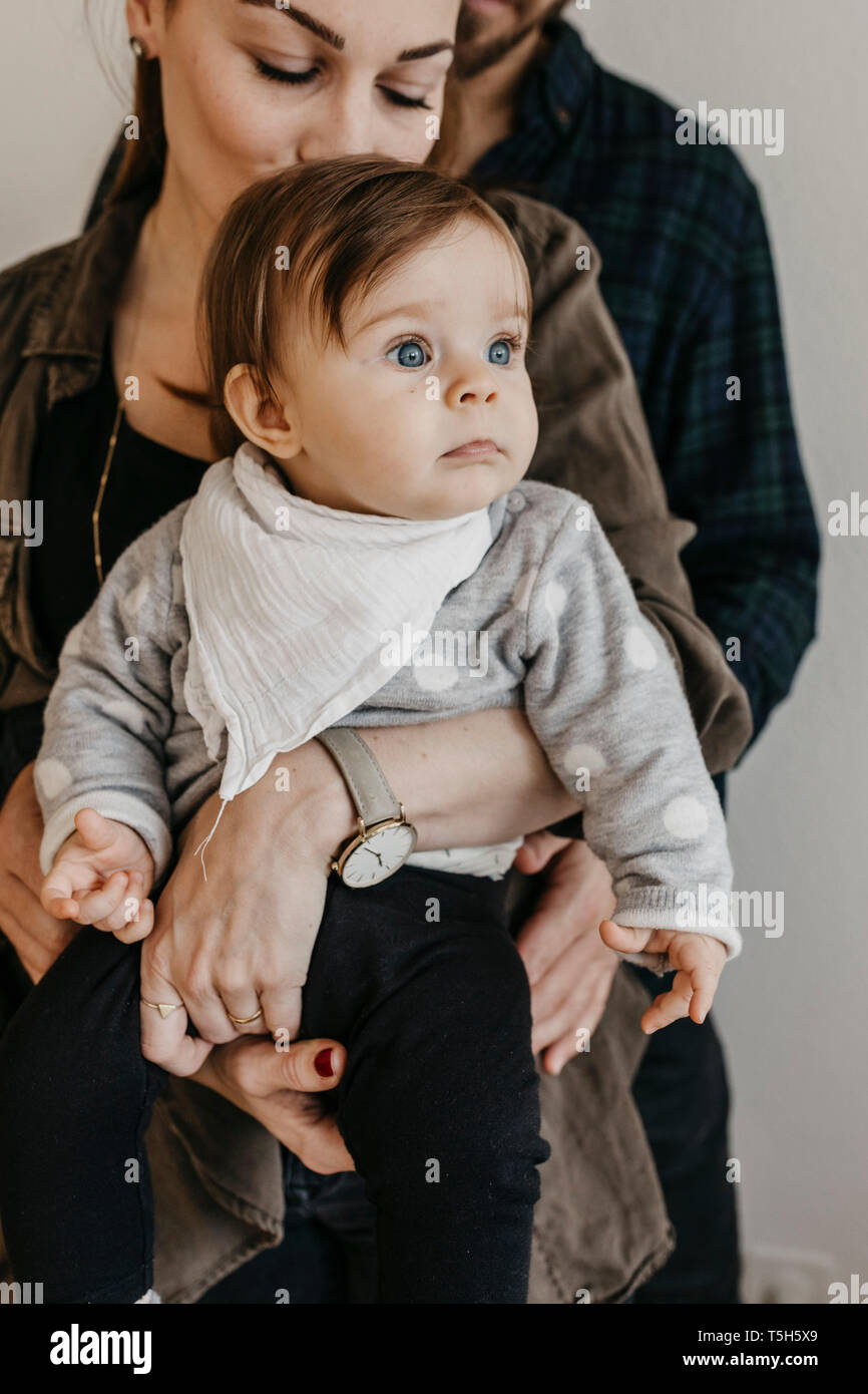 Parents holding baby girl looking away Stock Photo
