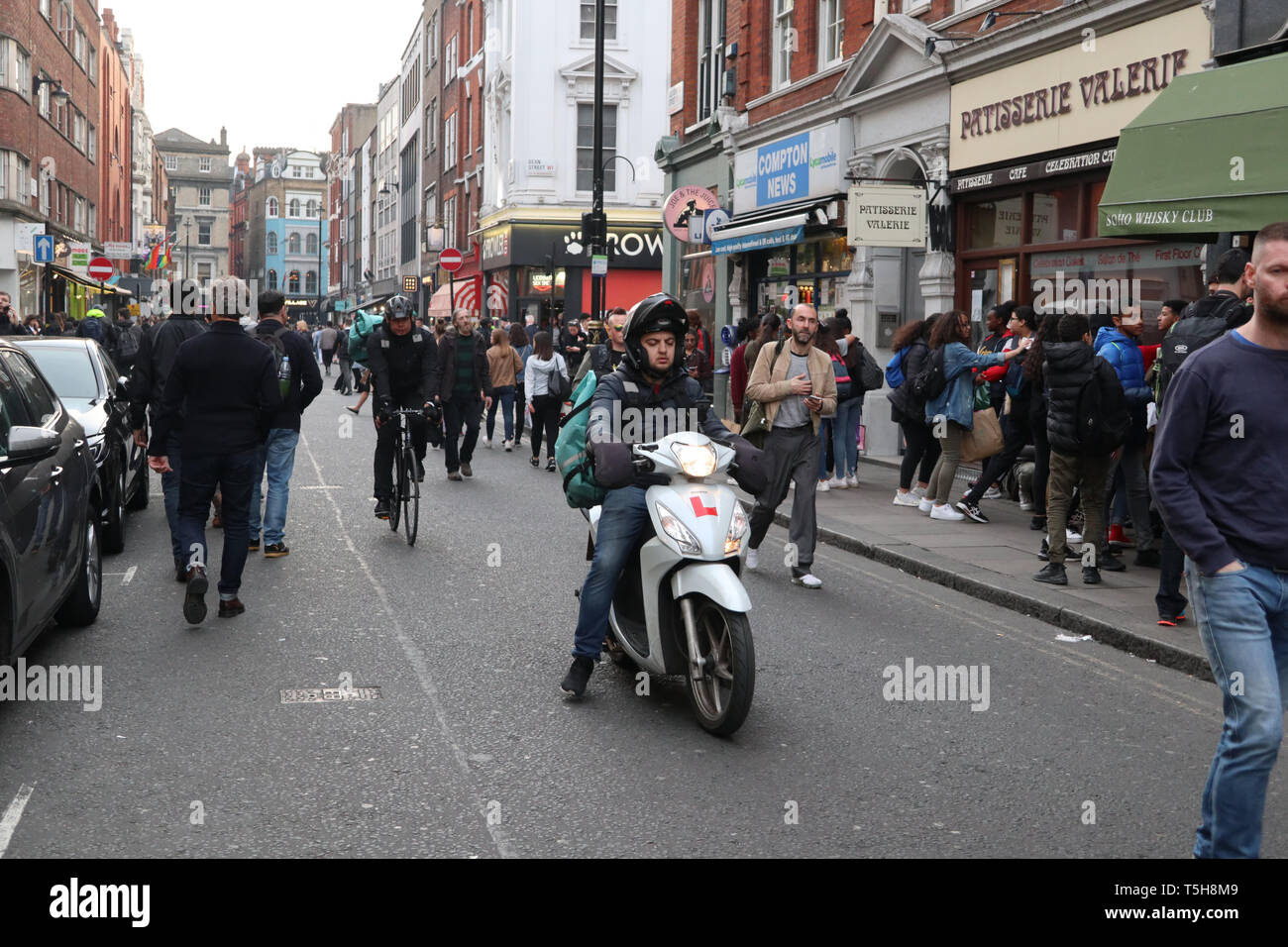 Deliveroo scooter & cyclist in Little Italy, Soho, London, England, UK Stock Photo