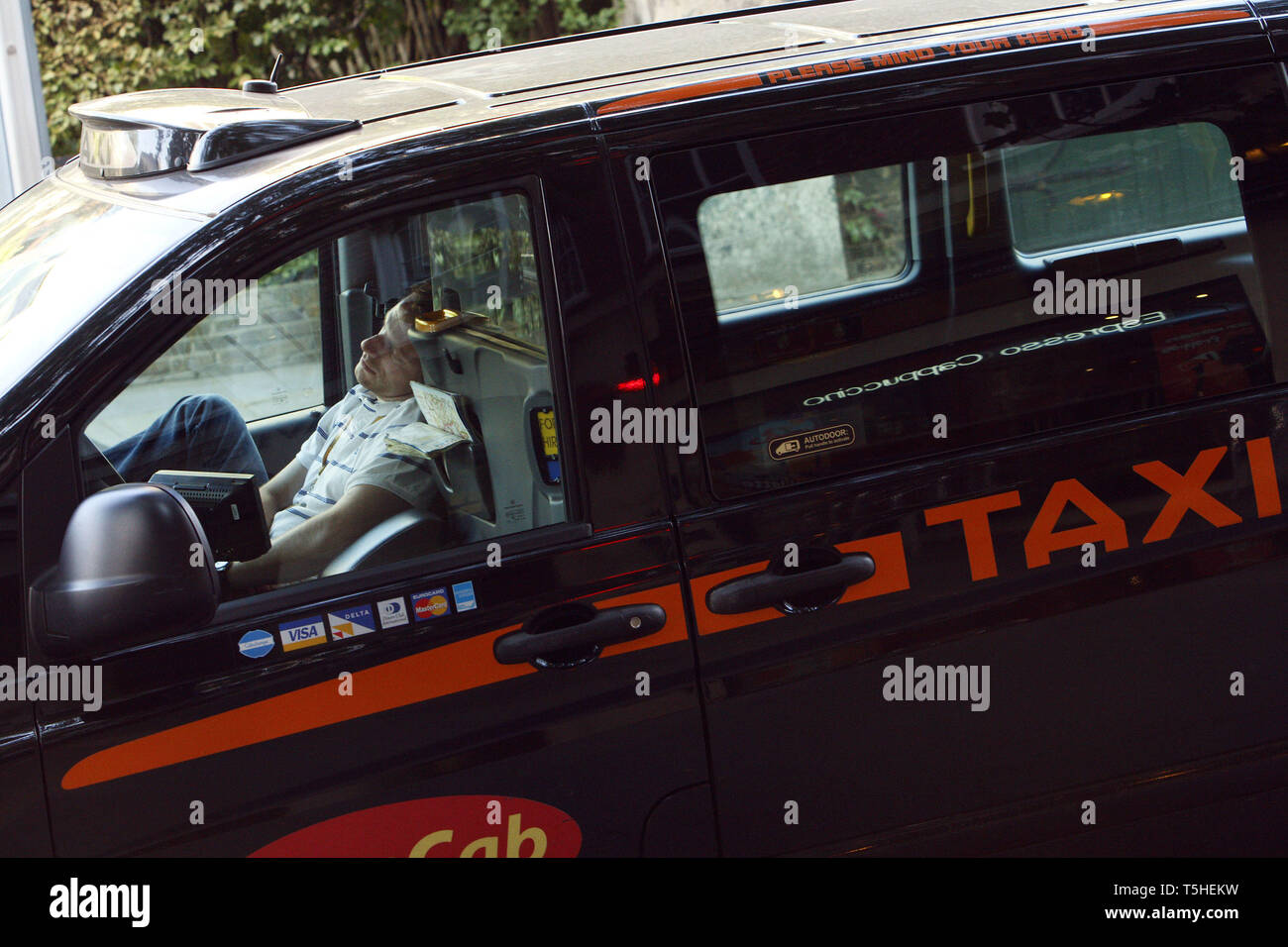 Exhausted taxi driver having getting some sleep whilst pulled over at the side of the road in his cab. London. 16.8.2010. Stock Photo