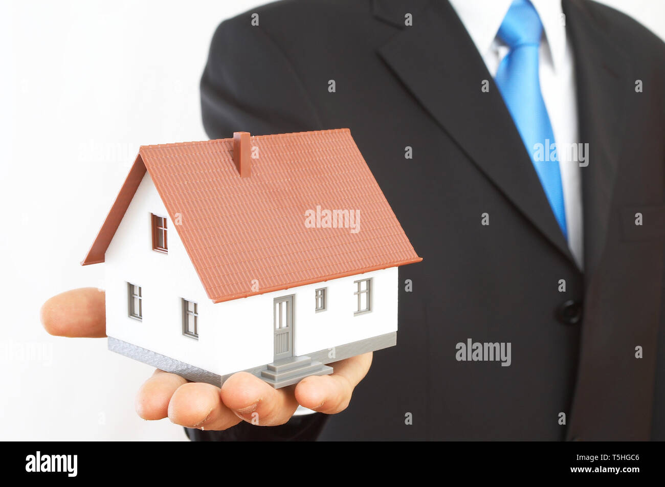 real estate concept with a mini house on white Stock Photo - Alamy