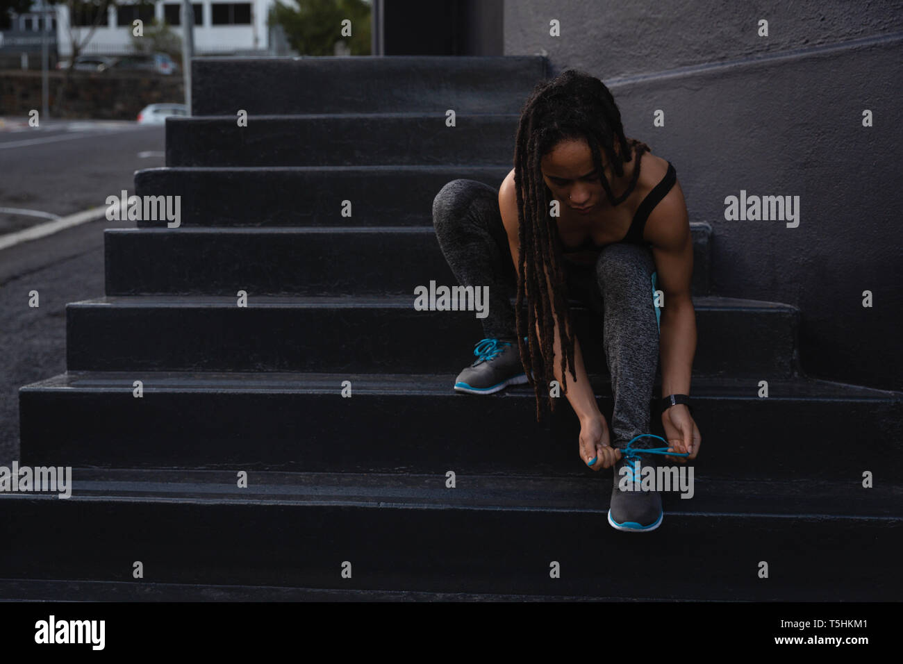 Young woman tying her shoelaces on stairs in the city Stock Photo