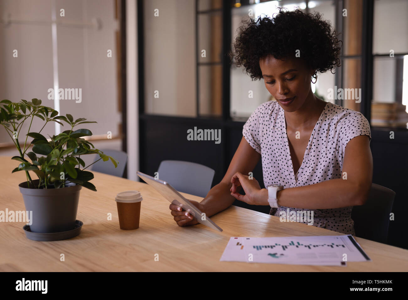 Businesswoman checking time while using digital tablet Stock Photo