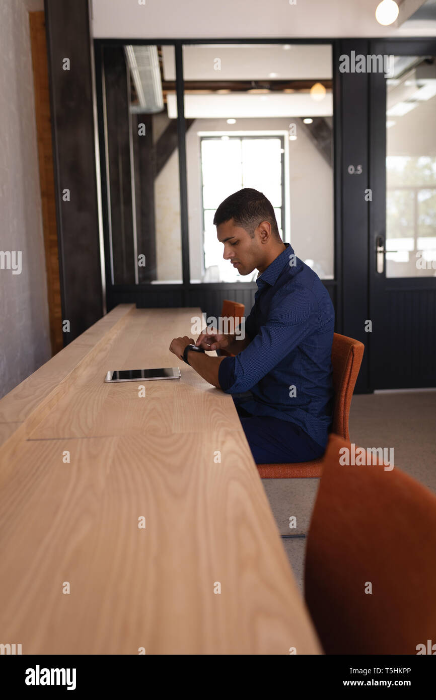 Businessman checking time while he is sitting on chair at office Stock Photo