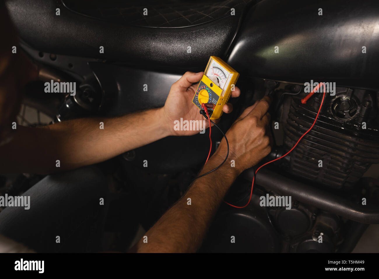 Bike mechanic checking battery of bike with multimeter Stock Photo