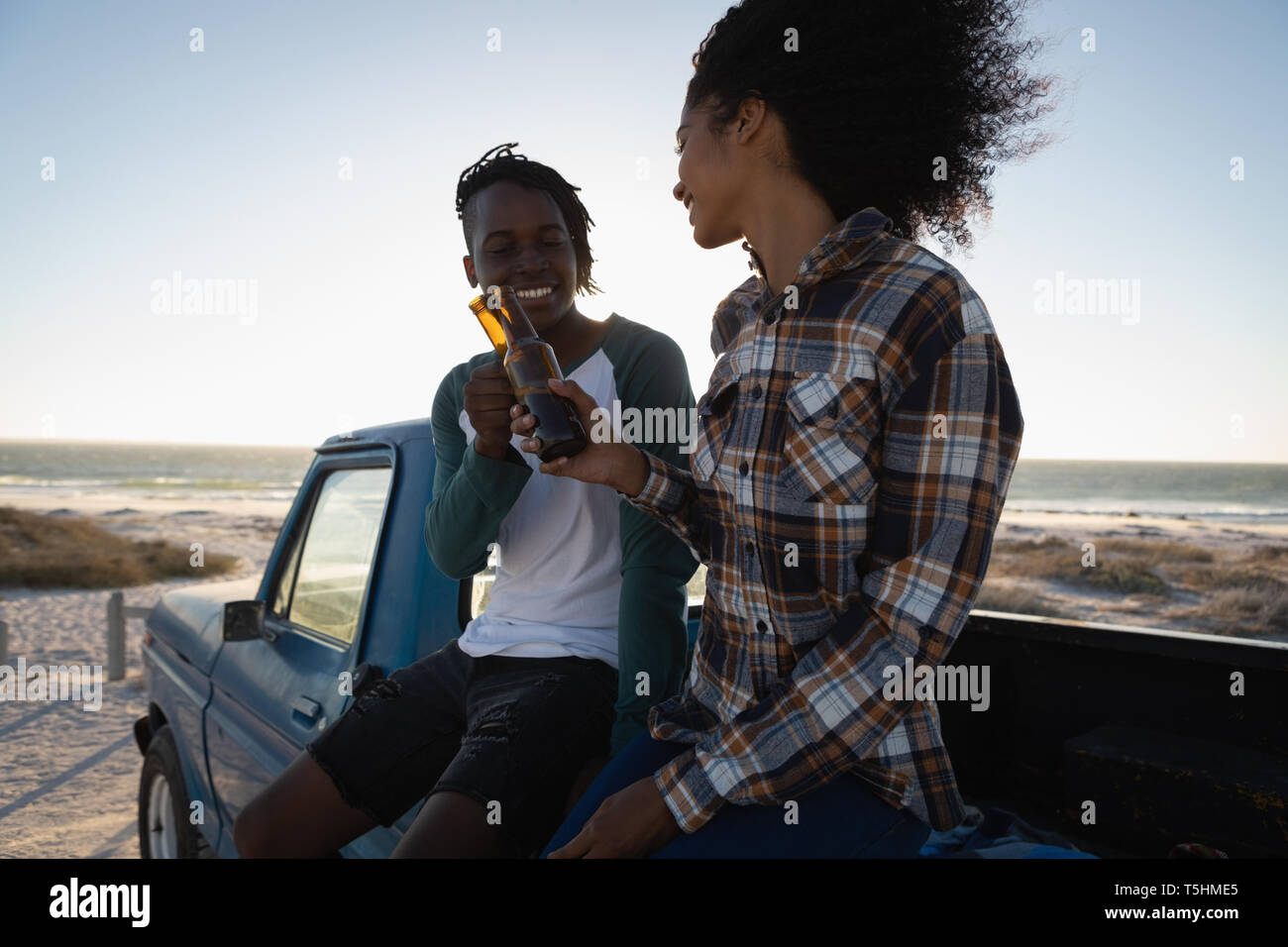Couple toasting beer bottle in car at beach Stock Photo