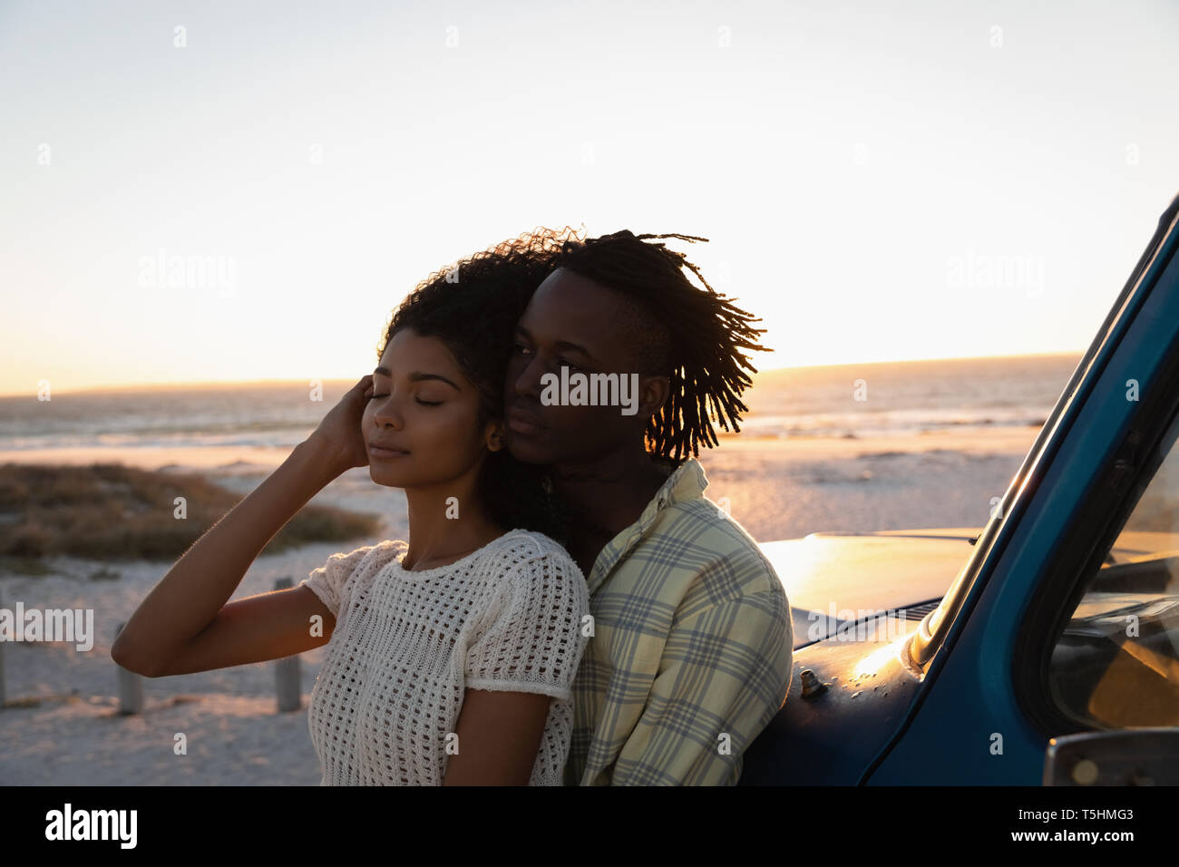 Romantic couple leaning at car on beach Stock Photo
