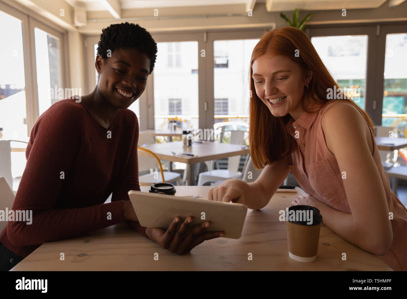 Female friends using digital tablet in a cafe Stock Photo