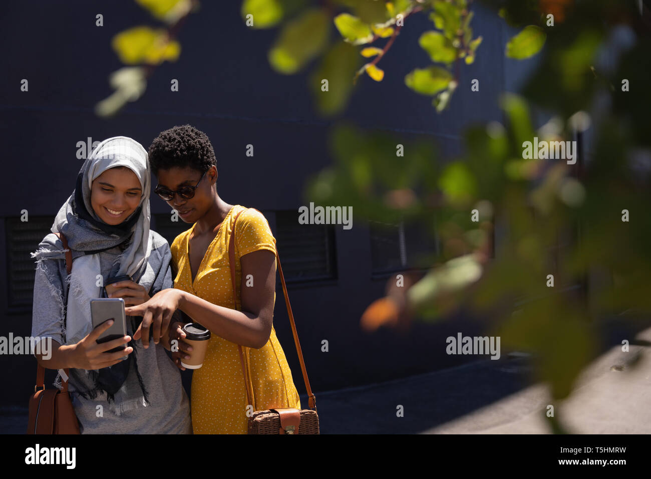 Female friends taking selfie with mobile phone in the city street Stock Photo