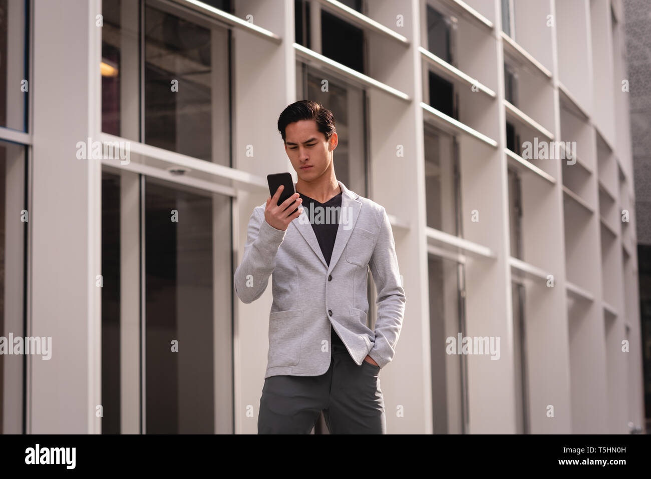 Handsome man using mobile phone while standing near building Stock Photo