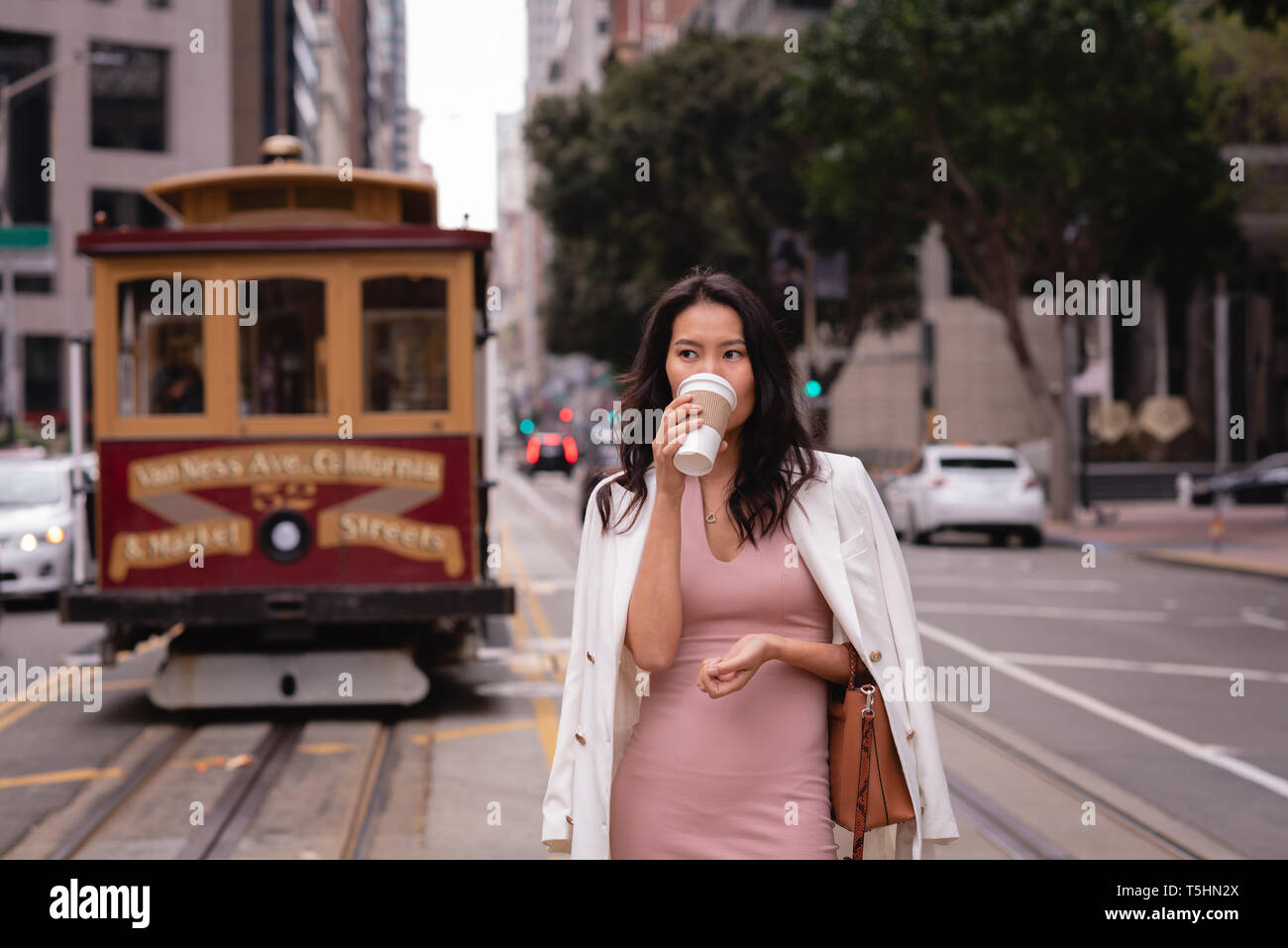 Thoughtful woman standing on street while having coffee Stock Photo