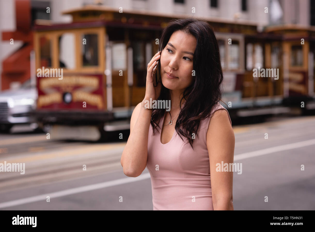 Beautiful woman talking on mobile phone while standing on street Stock Photo
