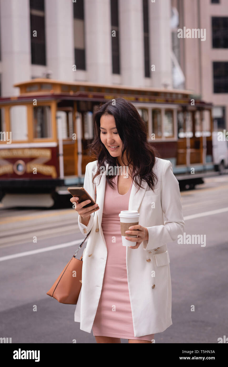 Beautiful woman using mobile phone while having coffee at street Stock Photo