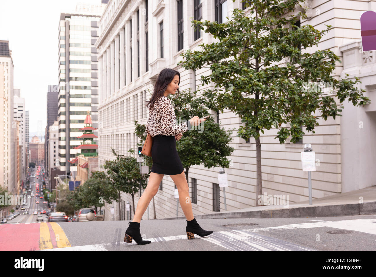 Beautiful woman using mobile phone while walking from street Stock Photo