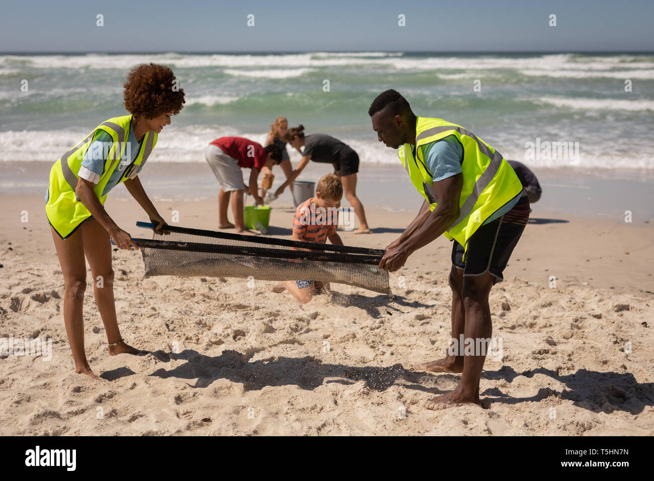 Volunteers cleaning beach on a sunny day Stock Photo