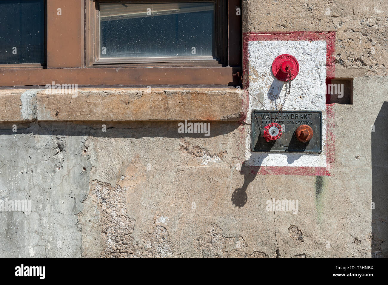 Wall hydrant for fire department connection in a crumbling concrete wall Stock Photo