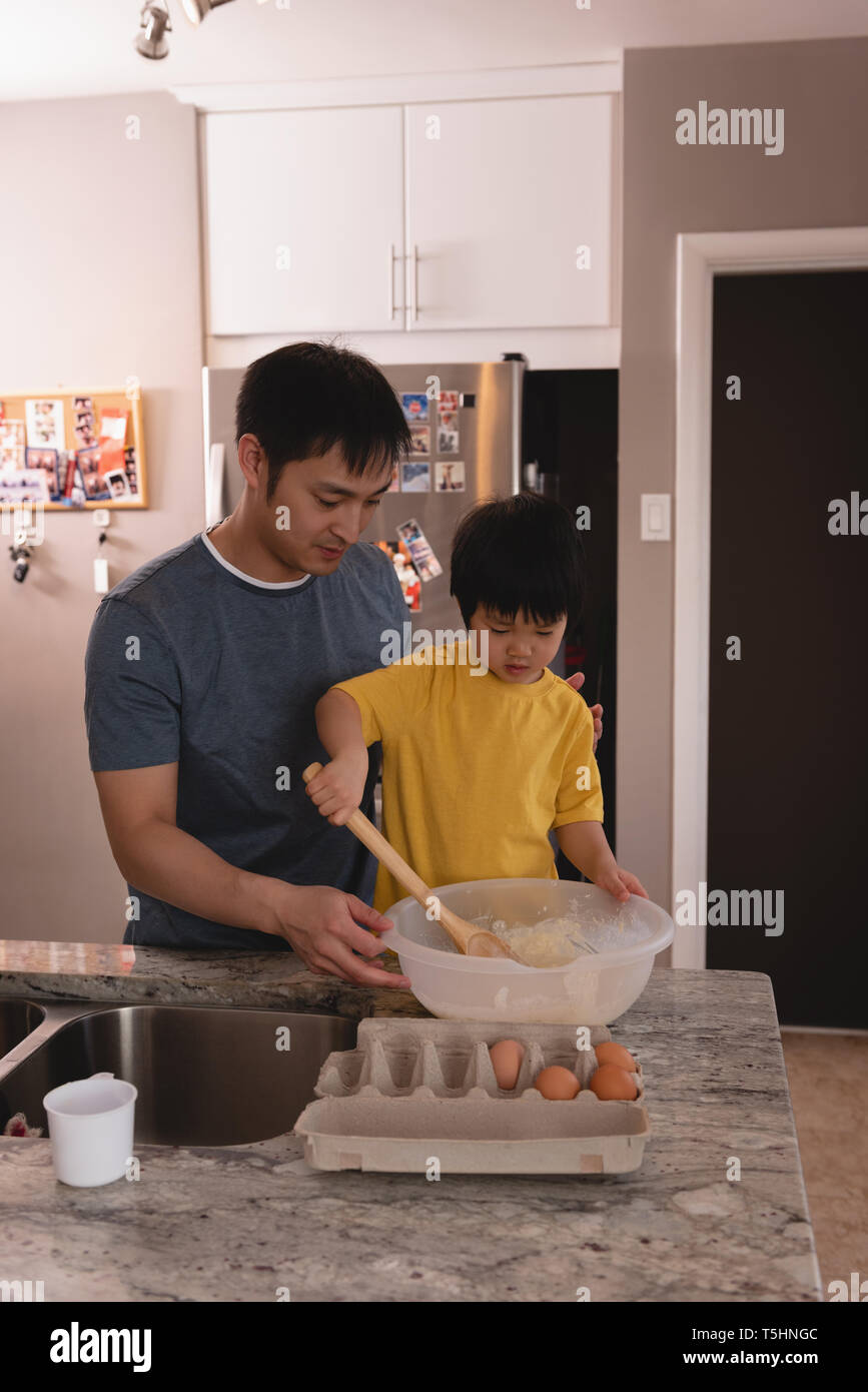 Father and son mixing dough together in kitchen at home Stock Photo