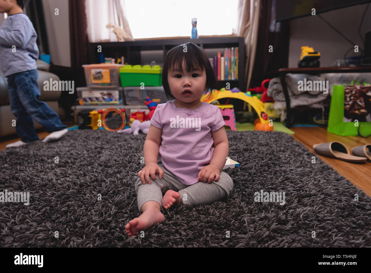 Small cute baby sitting on rug at home Stock Photo
