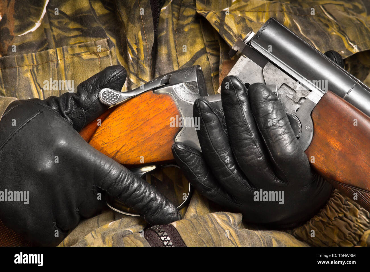 hands of hunter in camouflage loading the double-barreled shotgun, closeup Stock Photo