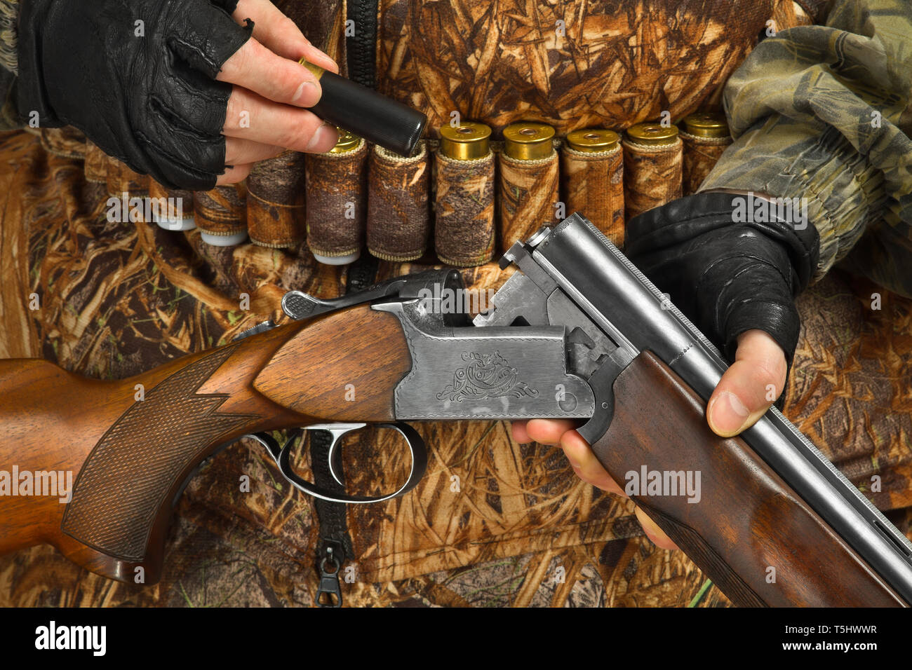 hands of hunter in camouflage loading shotgun, closeup Stock Photo