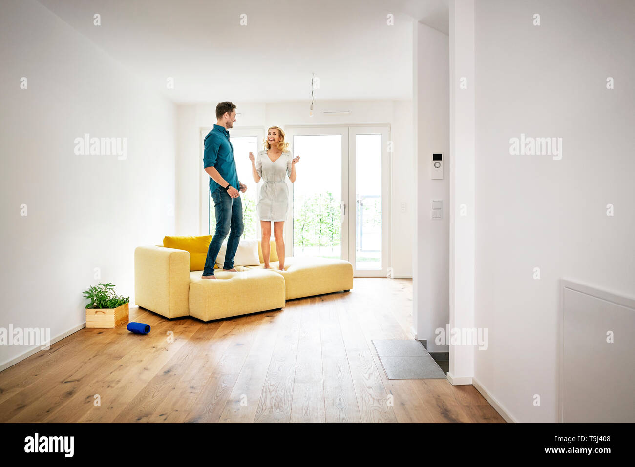 Couple jumping for joy on couch in their new home Stock Photo
