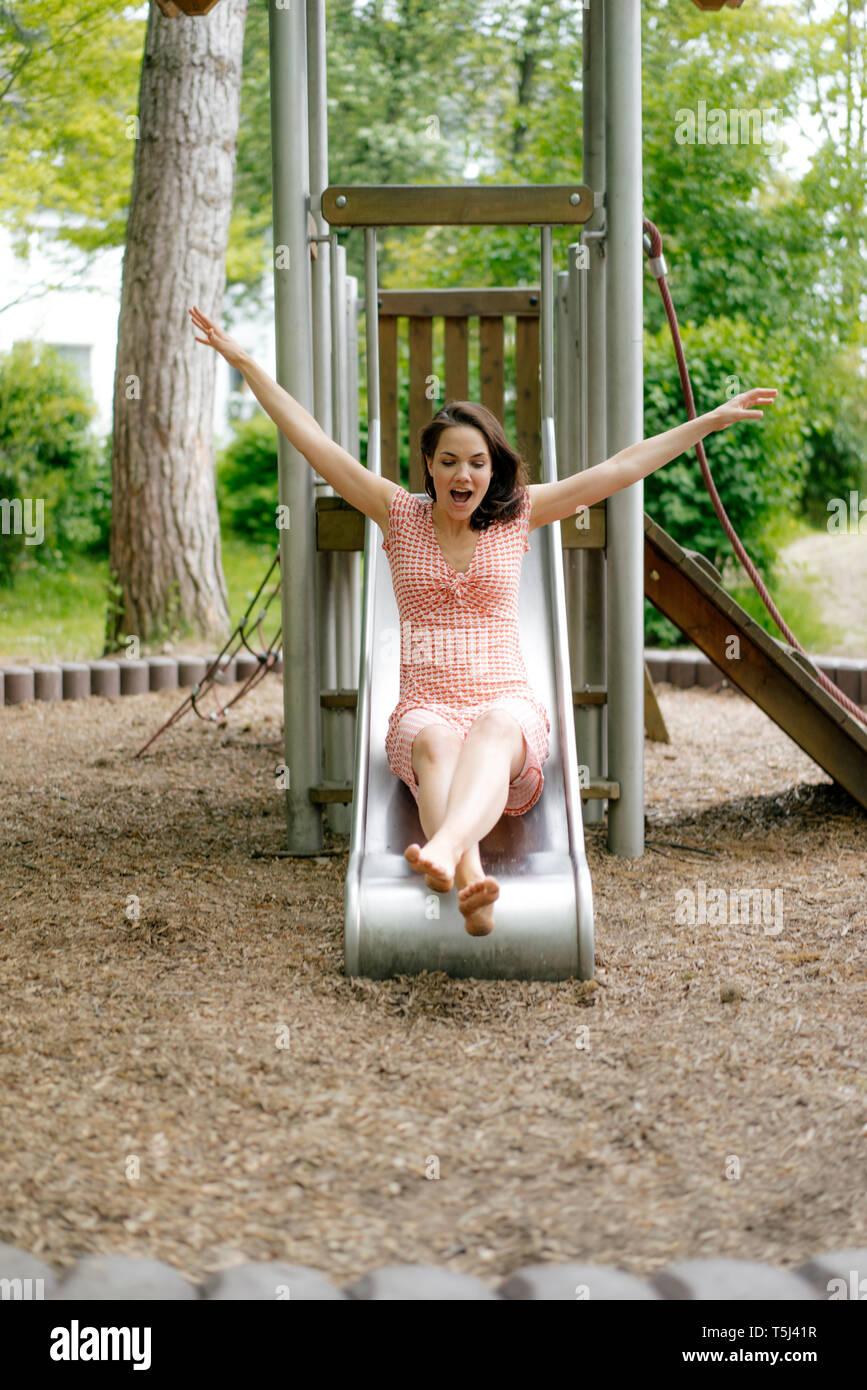 Woman sliding on a slide on a playground Stock Photo - Alamy