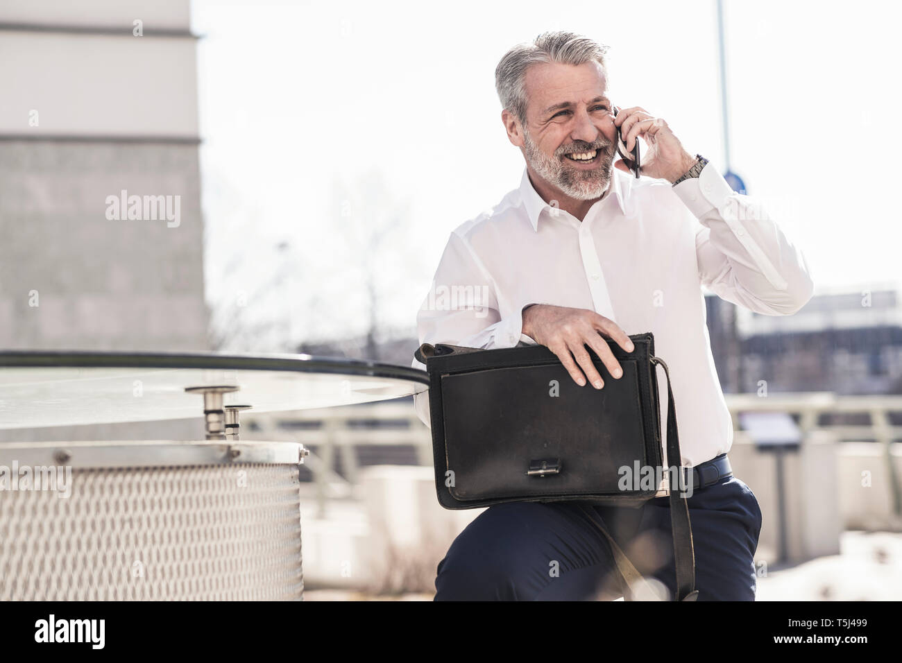 Happy mature businessman talking on cell phone outdoors Stock Photo