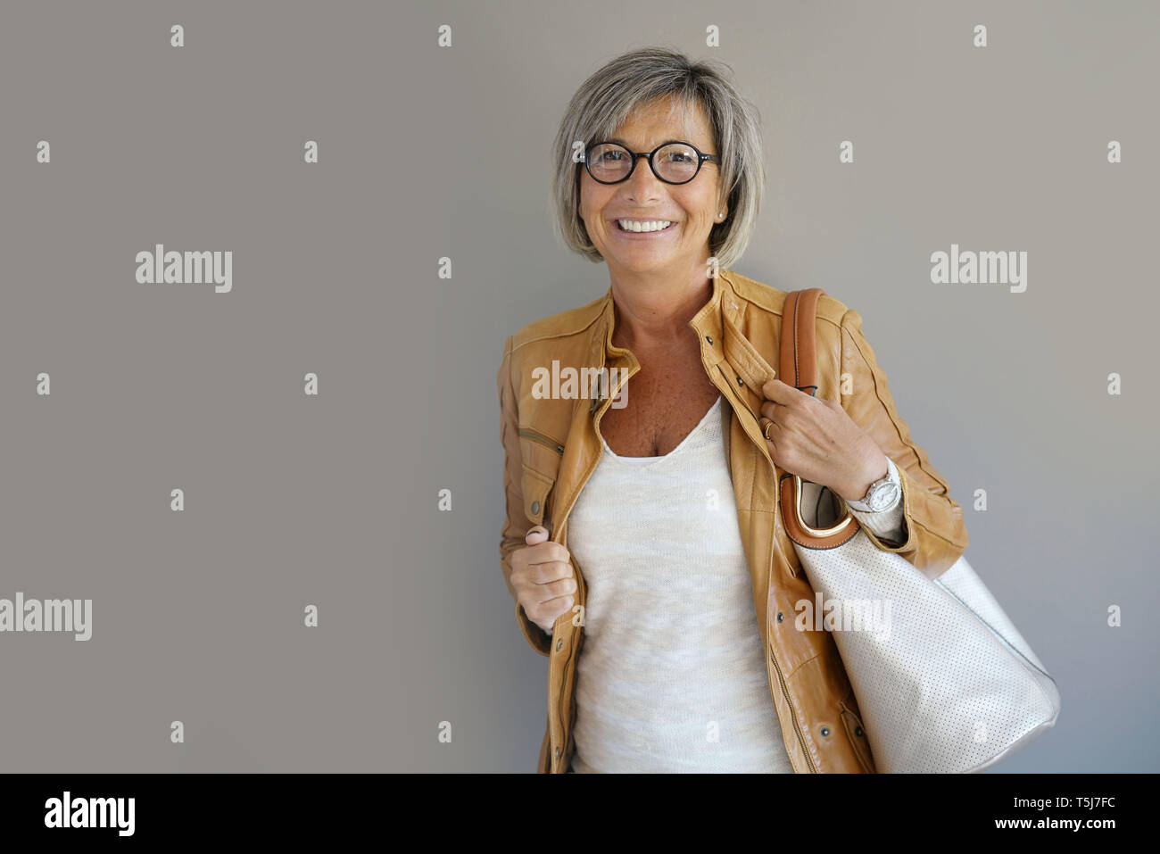 Modern mature woman standing on grey background Stock Photo - Alamy