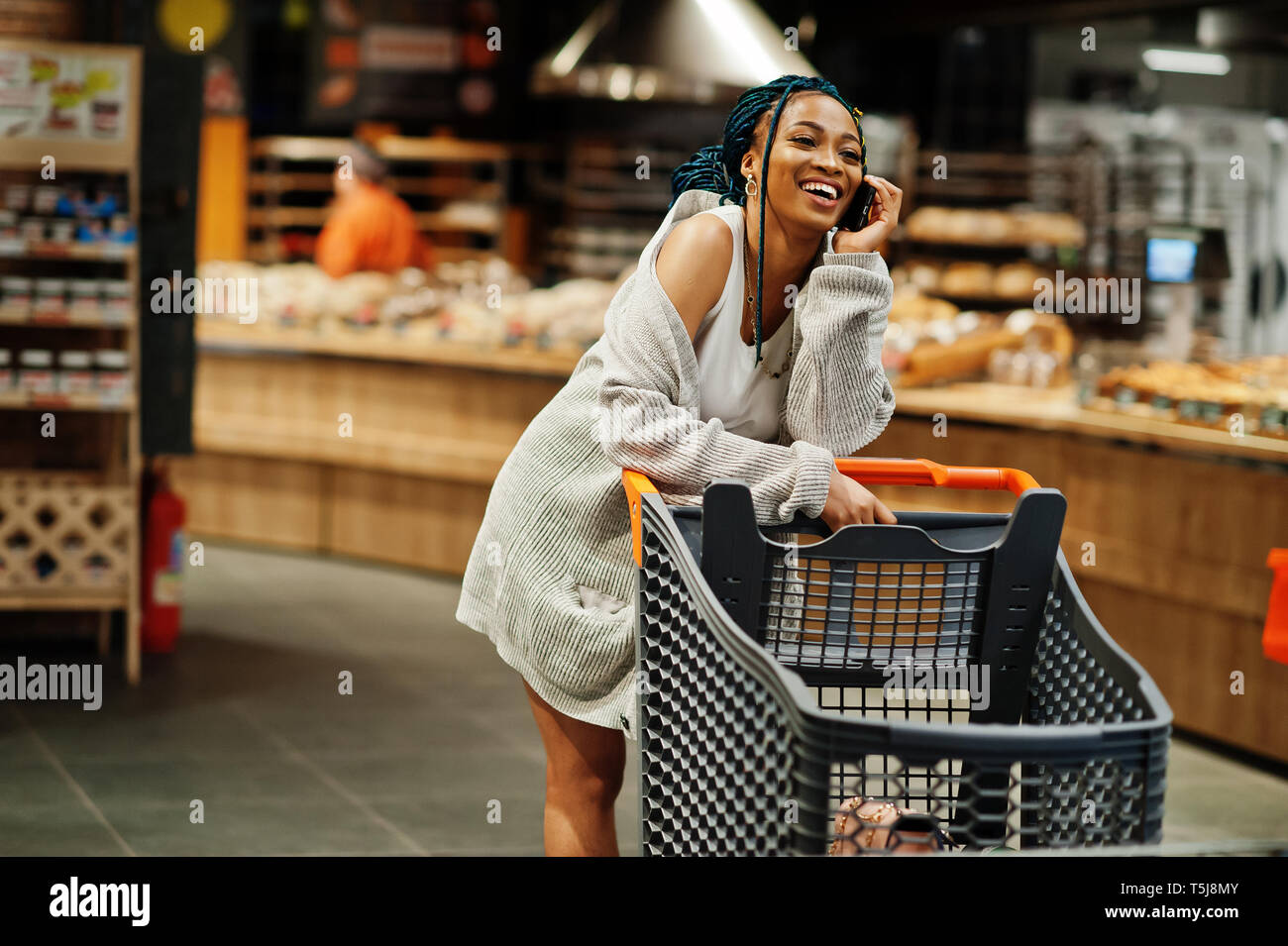 African american woman with shopping cart trolley in the supermarket store  speak on mobile phone Stock Photo - Alamy