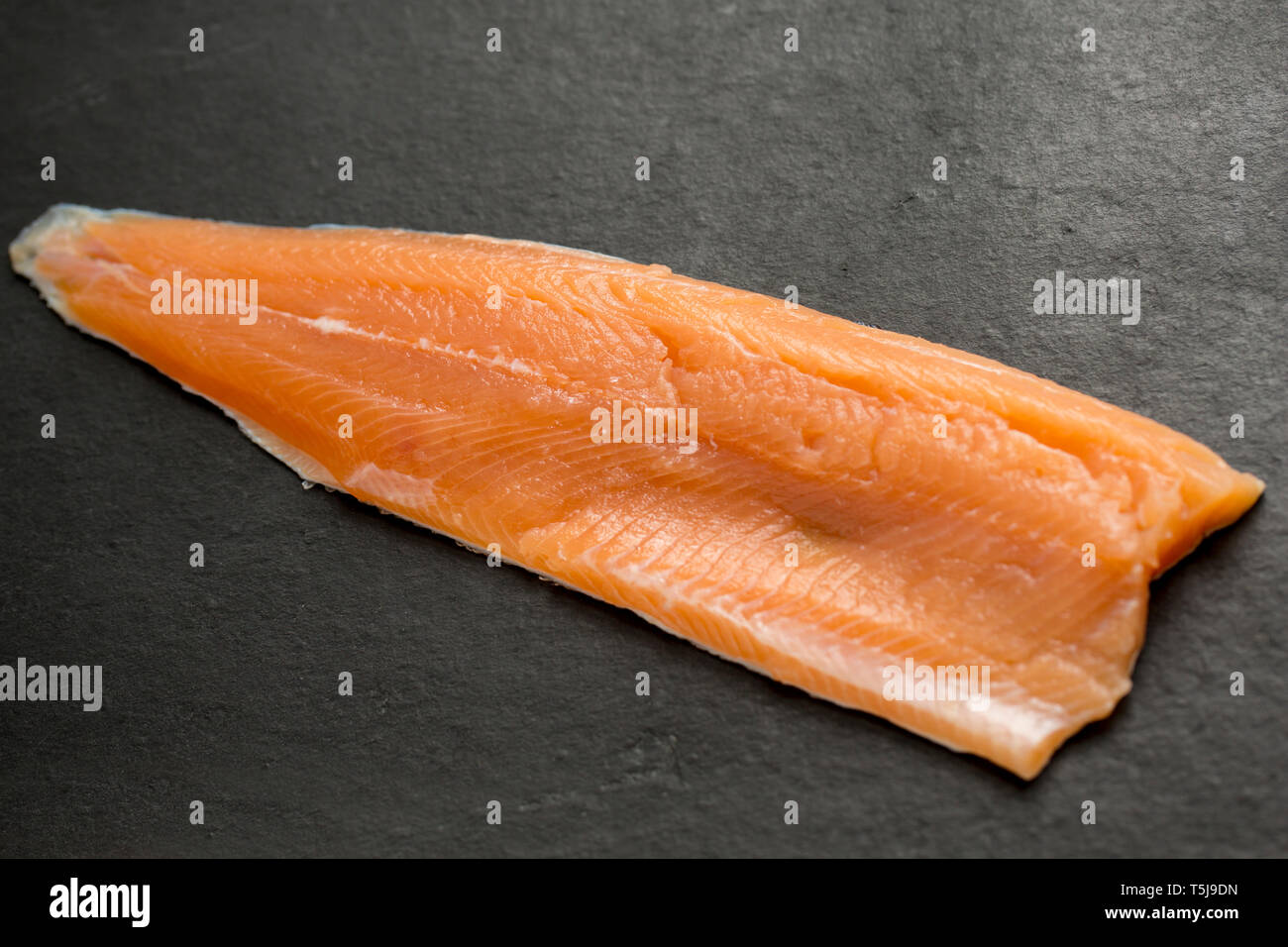 A single, raw fillet from a rainbow trout, Oncorhynchus mykiss, that was caught fly fishing in a put and take reservoir stocked with rainbow trout. Fi Stock Photo