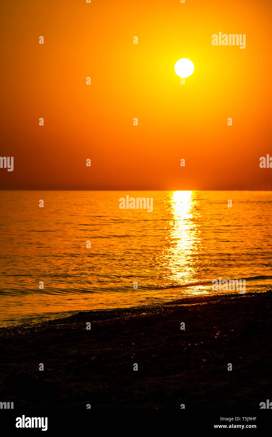 Vertical sunset coastline calm sea with golden sun - Late afternoon on beach waterline with golden direct sunset calm sea ocean - Sun sky sea ocean ni Stock Photo