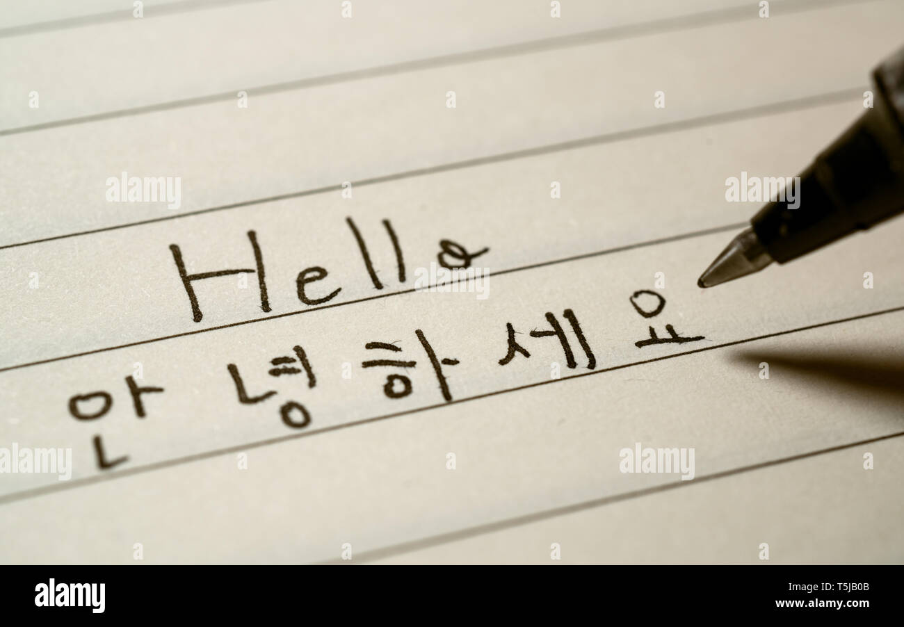 Beginner Korean language learner writing Hello word Annyeonghaseyo in Korean characters on a notebook close-up shot Stock Photo
