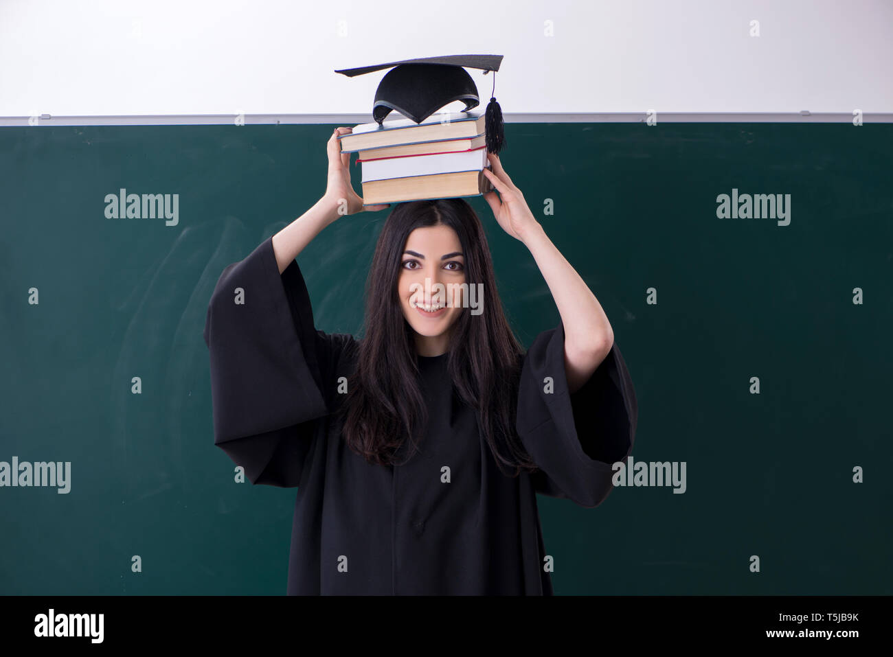 Female graduate student in front of green board Stock Photo - Alamy