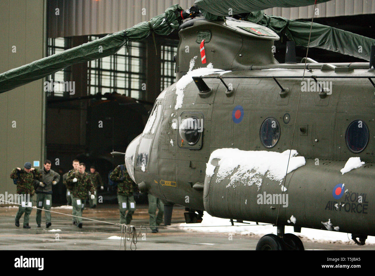 RAF personnel walking out of a hanger in the snow past a Chinook helicopter at RAF in Hampshire. 13.01.10 Stock Photo