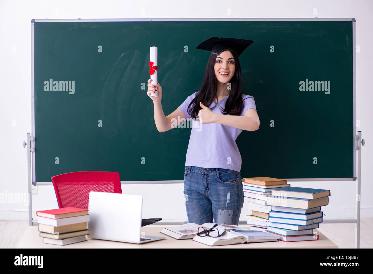 Female graduate student in front of green board Stock Photo - Alamy