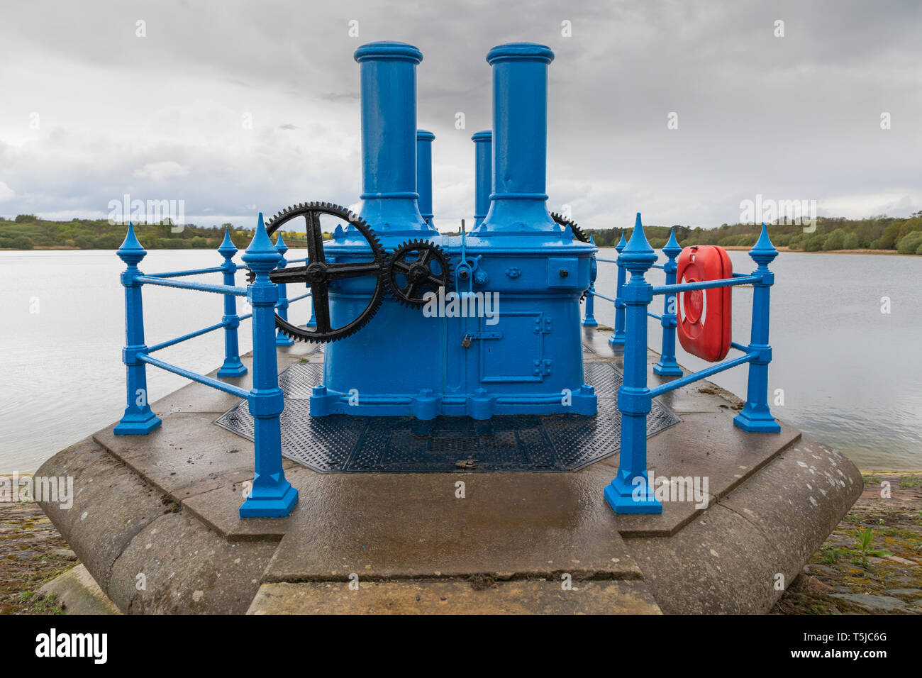 Ravensthorpe, Northamptonshire / UK - April 25th 2019: Blue valve gear housing with black gear wheels covered in rainwater droplets under a leaden sky. Stock Photo