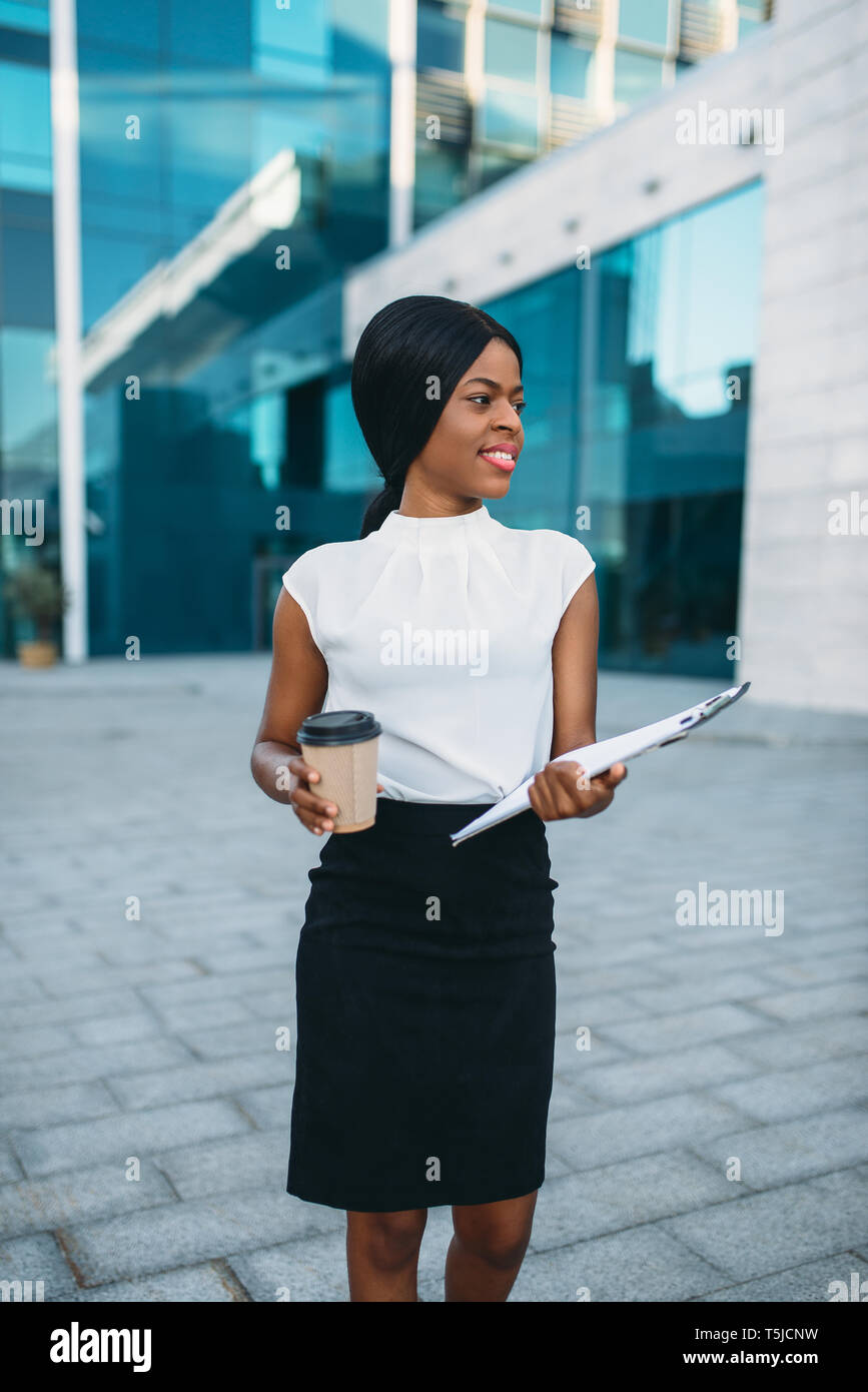 Business woman with cardboard coffee cup and notepad outdoors