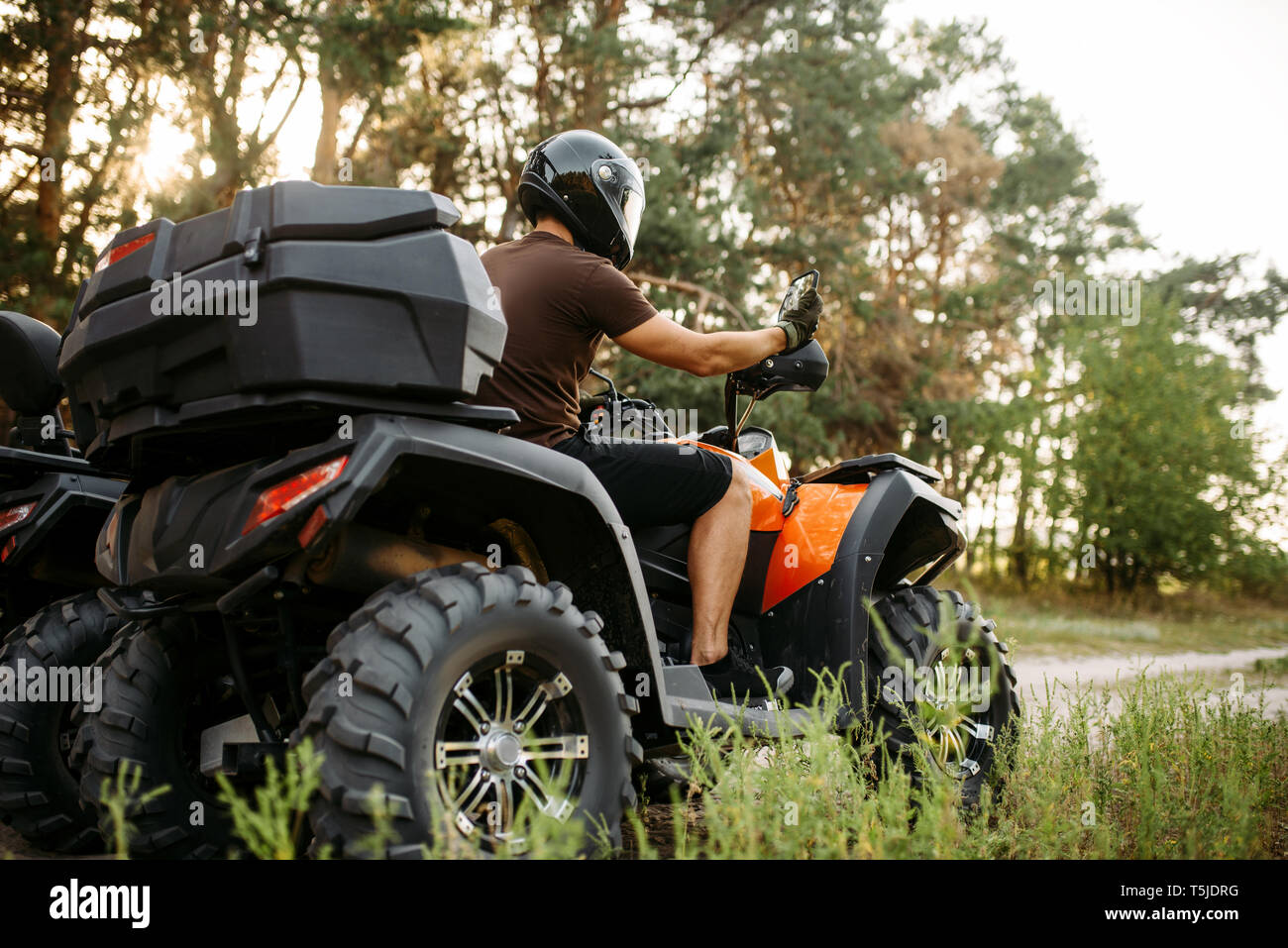 Rider in helmet and equipment on quad bike, front view, closeup. Male