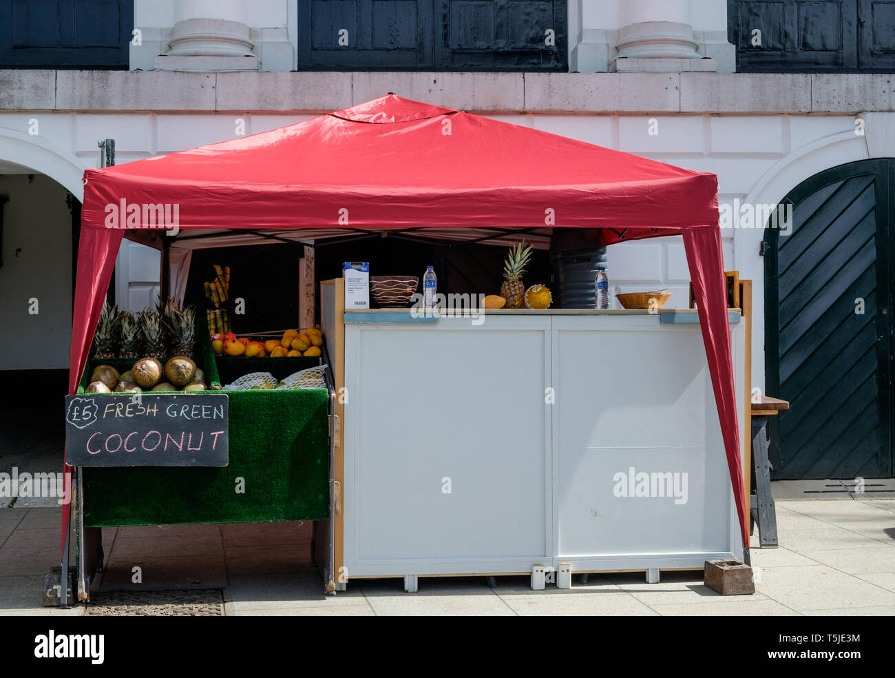 Kiosk with red tented roof next to Revolution London on Buccleuch Passage,selling fresh coconut and other foods. Richmond, London. May, 2018 Stock Photo