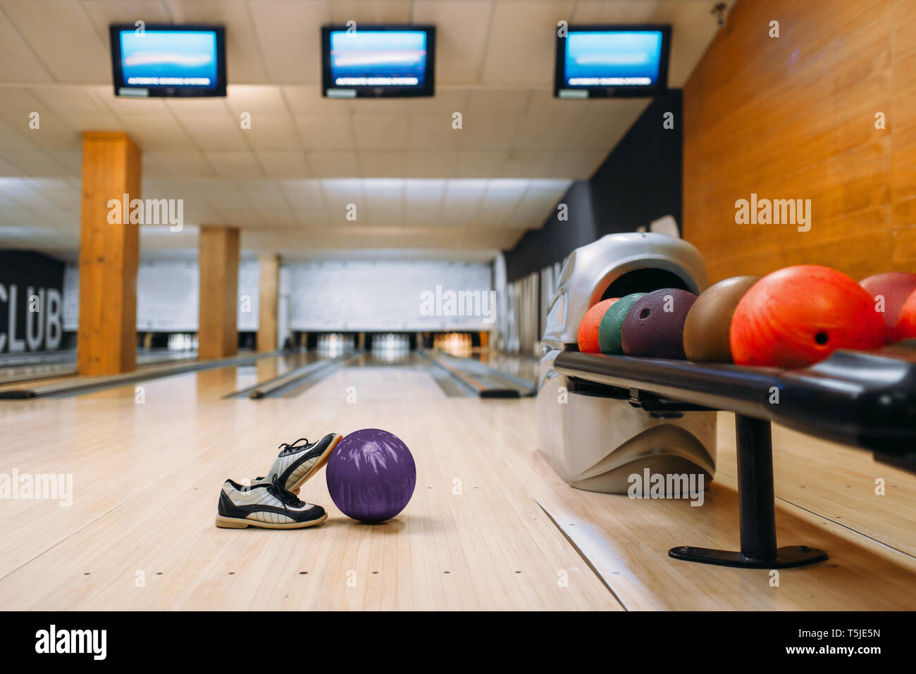 Bowling ball and house shoes on wooden floor in club, pins on background, nobody. Bowl game concept, tenpin Stock Photo