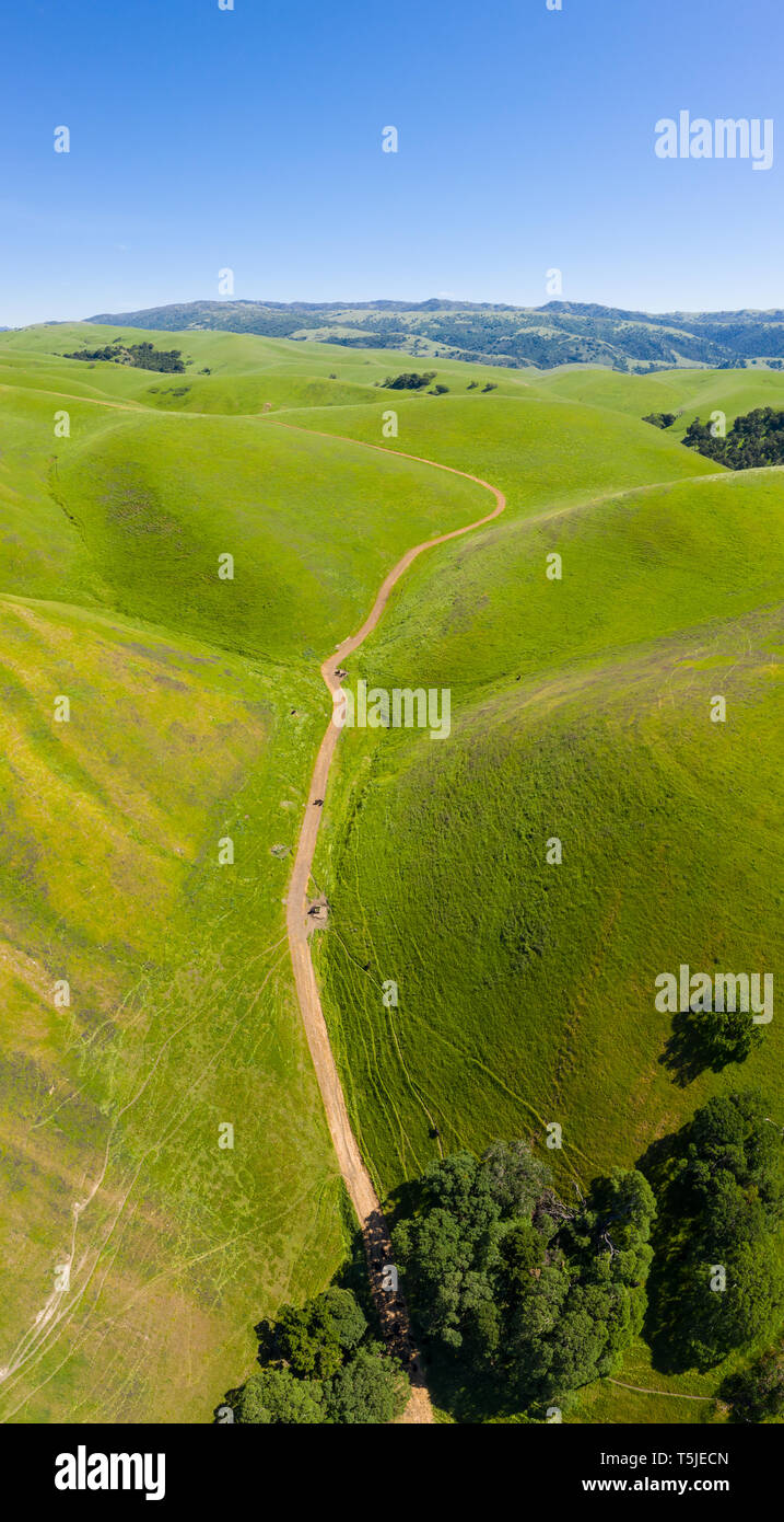 An aerial view of rolling hills in Northern California's tri-valley region shows lush, green grass that flourished after a wet winter. Stock Photo