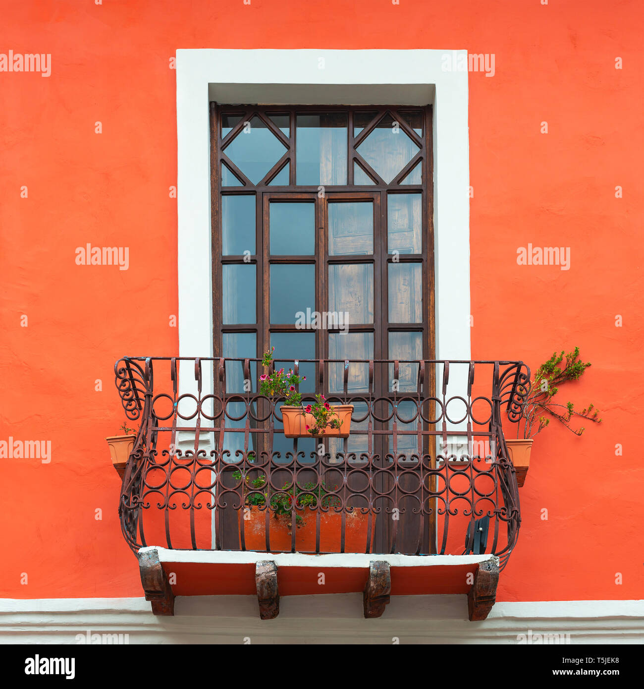 Colonial style balcony with window and living coral orange tone wall facade in the historic city center of Cuenca, Ecuador. Stock Photo