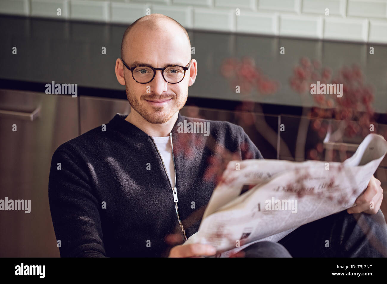 Man sitting in kitchen, reading newspaper Stock Photo